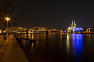 Cologne Cathedral (German: Kolner Dom, officially Hohe Domkirche St. Peter und Maria) and Hohenzollern Bridge across the Rhine, Germany, at dusk