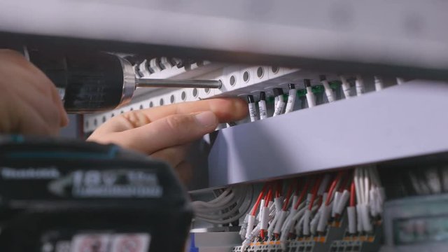 Engineer installing industrial electircal shield with the screw gun. 4K.