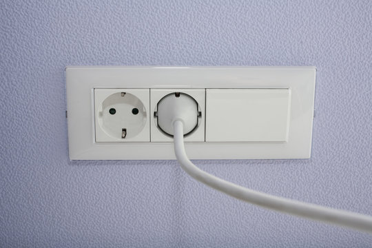 белая розетка с выключателем на сиреневой стене