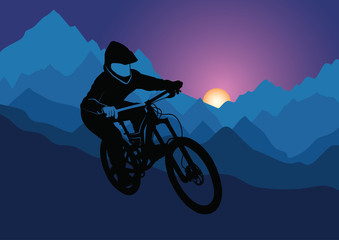 Silhouette of a racer descending on a bicycle on a mountainside against the background of the evening sun
