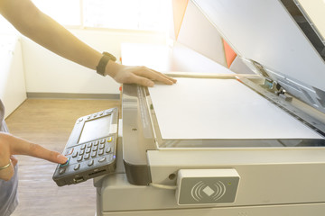 Man copying paper from Photocopier with access control for scanning key card sunlight from window