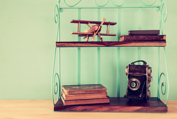 Vintage shelf with old wooden plane toy, books and decorative camera.