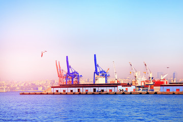 Istanbul, Turkey, Golden Horn creek of Bosporus. Container Cargo freight ship with working crane bridge in shipyard at dusk for Logistic Import Export background sunrise, sun light.