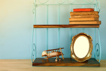 Vintage shelf with old wooden plane toy, books and blank photo frame