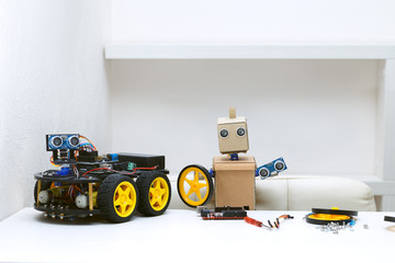 Obraz premium Two robots are on the table, around are parts for assembling the robot