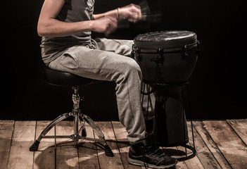 man playing a djembe drum and cymbals on a black background