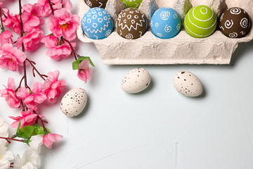 Painted easter eggs and branches of spring sakura closeup on a light blue background with space for congratulation