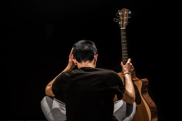 young man with acoustic guitar on black background