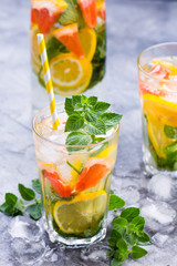 Cold refreshing summer lemonade in a glass on a grey concrete or stone background.