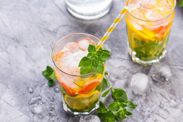 Cold refreshing summer lemonade in a glass on a grey concrete or stone background.
