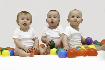 Fototapeta na wymiar Baby triplets engaged and playing with colorful balls