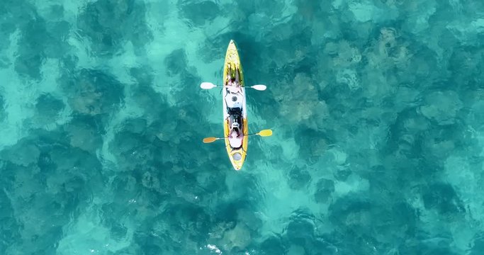 Aerial shot of couple kayaking in turquoise sea during summer day. Travel tropical island holiday concept