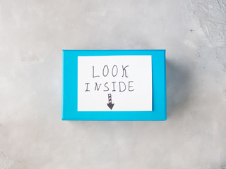 Blue gift box with paper card speling Look Inside. Surprise present concept. Top view