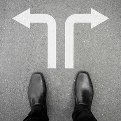 Businessman in black leather shoes standing at the crossroad making decision which way to go - two ways to choose.