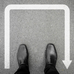 Businessman in black leather shoes standing at the u turn sign and can not go farther, have to retreat. © mantinov