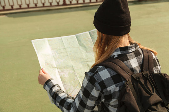 Woman tourist standing on a bridge with a map in hands