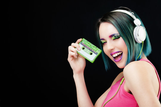 Portrait d'une jeune femme souriante, pr&eacute;sentant une cassette audio dans sa main