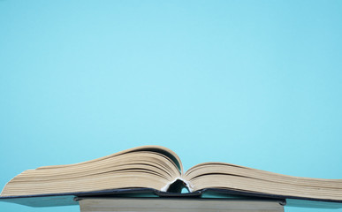 Open book, hardback books and blue wall .Education background. Back to school. Copy space for text.