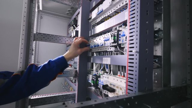 Electrician switching off electrical power, pushing switches in eletrical cabinets. 4K.