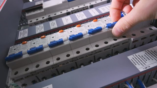 Professional electrician switch off electrical power, pushing switches in eletrical cabinets. 4K.