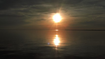 Naklejka na ściany i meble sunburst sunset reflecting on the water