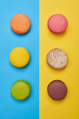 Top view of bright macaroons arranged in two line over blue flatlay