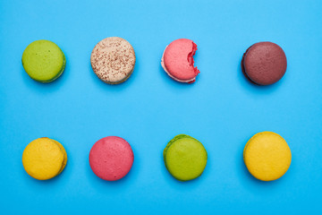 Bite macaroon lying among others on a blue flatlay