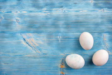 Easter eggs in soft colors on a blue shabby wooden table