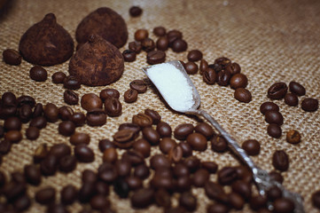 Coffee beans and chocolate candies on sackcloth close up. Coffee and sweets background.