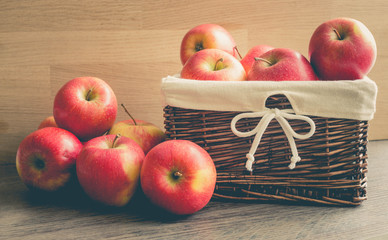 Juicy apples in the basket and scattered on the table.