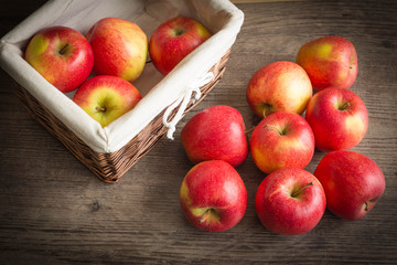 Juicy apples in the basket and scattered on the table.
