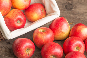 Juicy apples in the basket and scattered on the table.