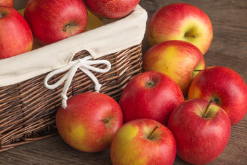 Juicy apples in the basket and scattered on the table.
