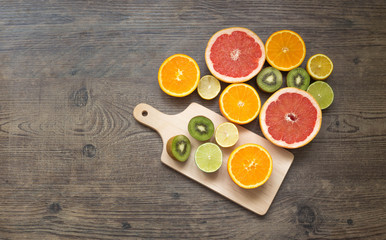  Slices fresh fruits on a brown table with cutting board with place for a text