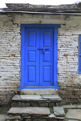Grunge gray bricks wall with blue door of Nepali house