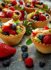 Berry tartlets with blueberries, raspberries, kiwi, strawberries, almond flakes in icing sugar.