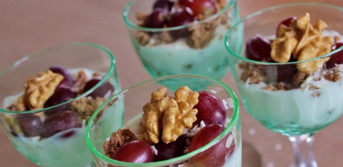 Individual portions of yoghurt with crunch, grapes, coconut flakes and walnut