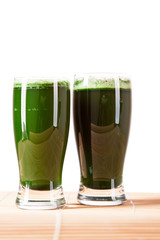 Green pills, green powder, green drink and wheat grass blades isolated on white background. Chlorella, spirulina, wheat grass and barley grass. Healthy natural herbal medicine, healthy lifestyle.