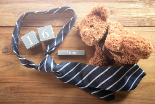 vintage wood calendar for june 16 with teddy bear and necktie Happy Father's Day inscription background concept.