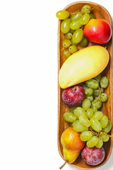 A large wooden bowl of fruit. Isolated white background. Mango, plum, pear, grapes, apple