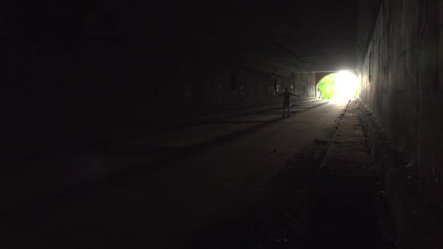 Man holds arms open as if he were an airplane flying through dark tunnel.
