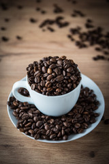 coffee cup filled by coffee beans on wooden background
