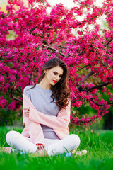 beautiful young girl sitting in the Park , a touch of spring