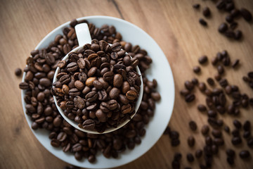 coffee cup filled by coffee beans on wooden background