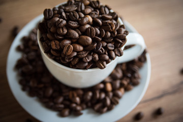 coffee cup filled by coffee beans on wooden background