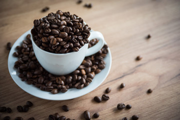 coffee cup filled by coffee beans on wooden background