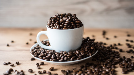 coffee cup filled by coffee beans on wooden background