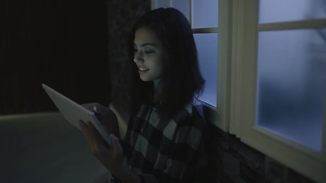 Teen girl using tablet PC in dark room before dream