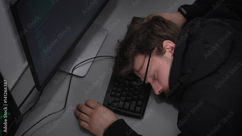 Poster young student of faculty on information technology is sleeping on keyboard in frint of computer moni
