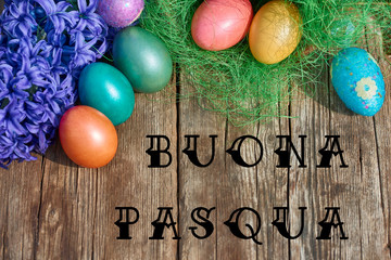 Easter eggs in nest on old wooden background with blue hyacinths flower and Text Buona Pasqua